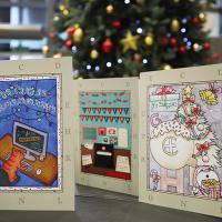 An image of a trio of Christmas Cards in the foreground. In the background is a Christmas tree.